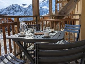 un tavolo in legno con sedie e un balcone con vista sulle montagne. di Appartement Orcières Merlette, 3 pièces, 6 personnes - FR-1-262-154 a Les Estaris