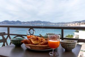 un cesto di pane e due bicchieri di succo d'arancia. di Palais Miramar - Suite & G17 - Vue Mer - Croisette Emplacement Unique -20 Plage - WIFI - Clim a Cannes Altre 14 foto