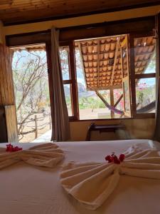 a bedroom with two towels on a bed with windows at Pousada Fulô da Pedra in Serra de São Bento