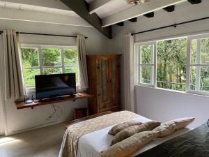 a bedroom with a bed and a flat screen tv at Dingo - Refugio romântico em meio à natureza in Penedo