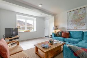 Dalveich Cottage, hot tub, 2 bedroom, Lochearnhead في لاكرنهيد: غرفة معيشة مع أريكة زرقاء وتلفزيون