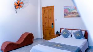 um quarto com uma cama, uma cadeira e uma porta em Lộc Sơn Hotel em Buon Ma Thuot