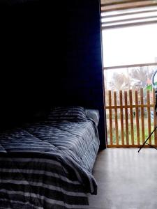 uma cama num quarto escuro com uma janela em Bugambilia house em Ica