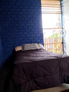 uma cama num quarto azul com uma parede de tijolos em Bugambilia house em Ica