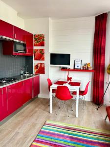 a kitchen with red cabinets and a table with red chairs at Appartement Le Lavandou in De Panne