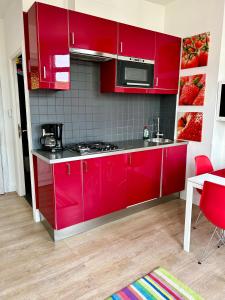 Czerwona kuchnia z czerwonymi szafkami i kuchenką mikrofalową w obiekcie Appartement Le Lavandou w mieście De Panne