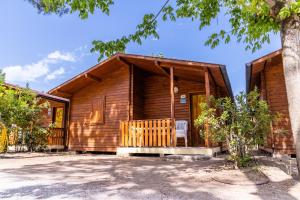 Cabaña de madera con porche y árbol en Italia Family Camping Village Viareggio, en Torre del Lago Puccini