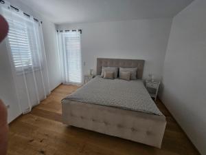 een slaapkamer met een groot bed en 2 ramen bij Apartamente Rognean in Wölfnitz