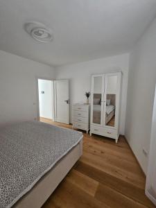 een slaapkamer met een bed, een dressoir en een spiegel bij Apartamente Rognean in Wölfnitz