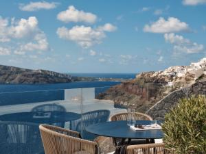 Olvos Luxury Suites في أويا: طاولة وكراسي على شرفة مطلة على المحيط