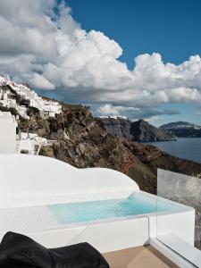 einen Pool mit Blick auf das Meer und die Gebäude in der Unterkunft Olvos Luxury Suites in Oia