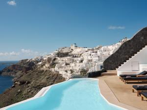 a pool with a view of a hill with white buildings at Olvos Luxury Suites in Oia