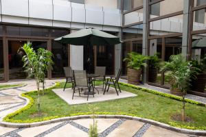 a table and chairs with an umbrella in front of a building at Gloria Inn Hotel - Ndola in Ndola