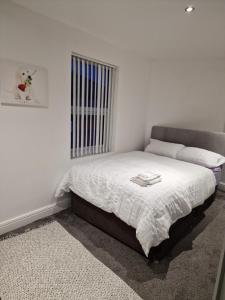 um quarto com uma cama com lençóis brancos e uma janela em Beautiful Double Bedroom em Liverpool