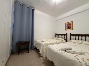 2 camas en una habitación con cortinas azules en Apartamentos Santa Rosa Palmyra, en Salou