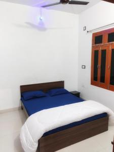 - une chambre blanche avec un lit bleu dans l'établissement SiyaRam Homestay, à Faizābād