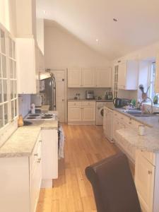 a large kitchen with white cabinets and wooden floors at Beautiful Airbnb with Ensuite Rooms in Shenley Church End