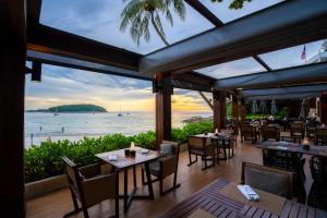 a restaurant with tables and chairs and a view of the ocean at The Nai Harn in Nai Harn Beach
