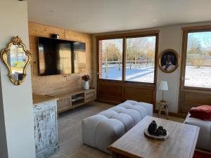 een woonkamer met een bank en een tv bij Gîte le Terrier in Hotot-en-Auge
