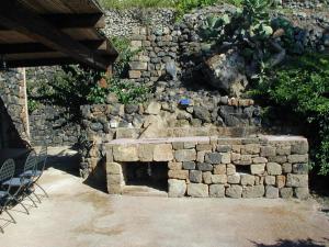 eine Steinbank vor einer Steinmauer in der Unterkunft Holiday home Dammuso Magia in Pantelleria