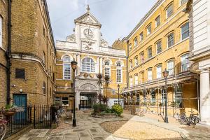 a large building with a clock tower in a courtyard at Converted Brewery Apartment with Terrace in London