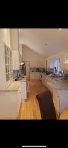a large kitchen with white cabinets and a wooden floor at Beautiful Airbnb with Ensuite Rooms in Shenley Church End