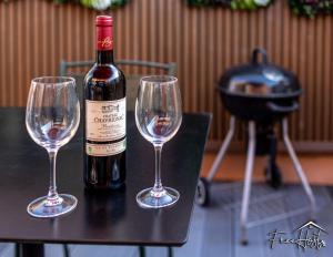 uma garrafa de vinho e dois copos de vinho numa mesa em Marvel House - Disneyland 5min, Private Parking, Terrace em Magny-le-Hongre
