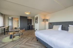 エイマイデンにあるLeonardo Hotel IJmuiden Seaport Beachの大きなベッドとテーブルが備わるホテルルームです。