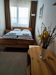 Un dormitorio con una cama y una mesa con un jarrón. en St. Benedek Apartmanlakás, en Mezőkövesd