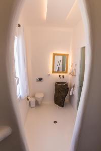 La salle de bains blanche est pourvue de toilettes et d'un miroir. dans l'établissement SALT SUITES MILOS, à Pollonia