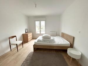 ein Schlafzimmer mit einem Bett, einem Stuhl und einem Fenster in der Unterkunft Ker Heol - Maison au Nord Finistère in Lesneven