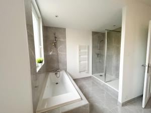 ein weißes Bad mit einer Badewanne und einer Dusche in der Unterkunft Ker Heol - Maison au Nord Finistère in Lesneven