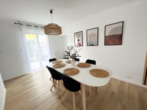 a white dining room with a white table and chairs at Ker Heol - Maison au Nord Finistère in Lesneven