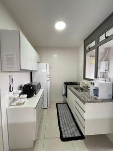 a white kitchen with a sink and a refrigerator at TULUM Bertioga - belo apartamento com vista para o mar in Bertioga