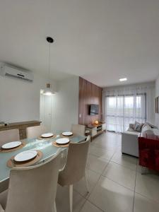 a kitchen and living room with a table and chairs at TULUM Bertioga - belo apartamento com vista para o mar in Bertioga