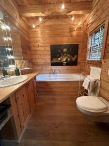 ein Holzbadezimmer mit einer Badewanne, einem WC und einem Waschbecken in der Unterkunft EifelChalet Arduina mit Wintergarten und Saunahaus im Naturpark Hohes Venn- Eifel in Hellenthal
