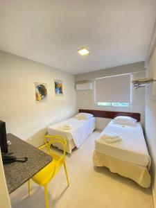 a room with two beds and a desk and a television at NORTH HOTEIS in Montes Claros
