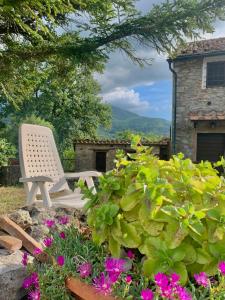 a white chair sitting in a garden with flowers at Borgo Petraio in Montieri