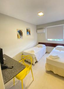 a hotel room with two beds and a table and a yellow chair at NORTH HOTEIS in Montes Claros