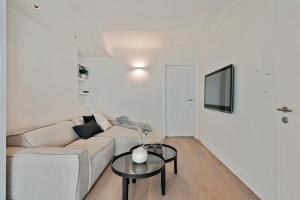 een witte woonkamer met een bank en een tafel bij Stunning fully renovated apartment with panoramic sea-view in 't Zoute with 2 parkings in Knokke-Heist