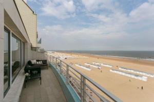 een uitzicht op een strand met parasols en de oceaan bij Stunning fully renovated apartment with panoramic sea-view in 't Zoute with 2 parkings in Knokke-Heist