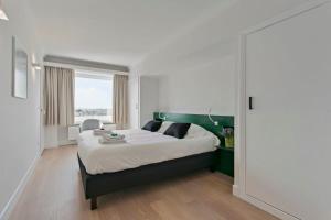 een slaapkamer met een groot bed met een groen hoofdeinde bij Huswell - Panoramic seaview apartment in 't Zoute in Knokke-Heist