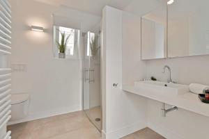 een witte badkamer met een wastafel en een douche bij Huswell - Panoramic seaview apartment in 't Zoute in Knokke-Heist +18 foto's