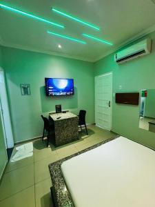 1 dormitorio con mesa y TV en la pared en Pousada Ponta Negra en Manaus