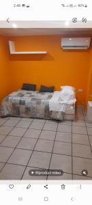 Cama en habitación con pared de color naranja en Relais Maria Luisa Locazione turistica di Simona Capaccio, en Fiumicino