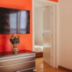 een kamer met een oranje muur en een vaas met bloemen bij Lovely 1-bedroom APT w/ seaview + free parking in Trogir