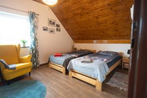 een slaapkamer met 2 bedden en een gele stoel bij CHILL Village in Nowinka +87 foto's