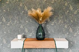 a green vase with feathers in it sitting on a table at Casa Vega — Luxury suite, banks of the River Orne in Caen
