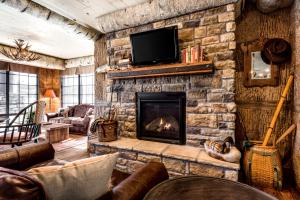 a living room with a stone fireplace with a tv at Bass Pro Shops Angler's Lodge in Springfield