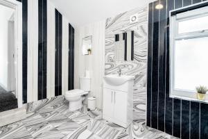 a bathroom with a black and white patterned wall at Large 5 Bedroom Edgbaston Townhouse - 10 Guests - Free WIFI, Netflix & On street Parking - 974P in Birmingham